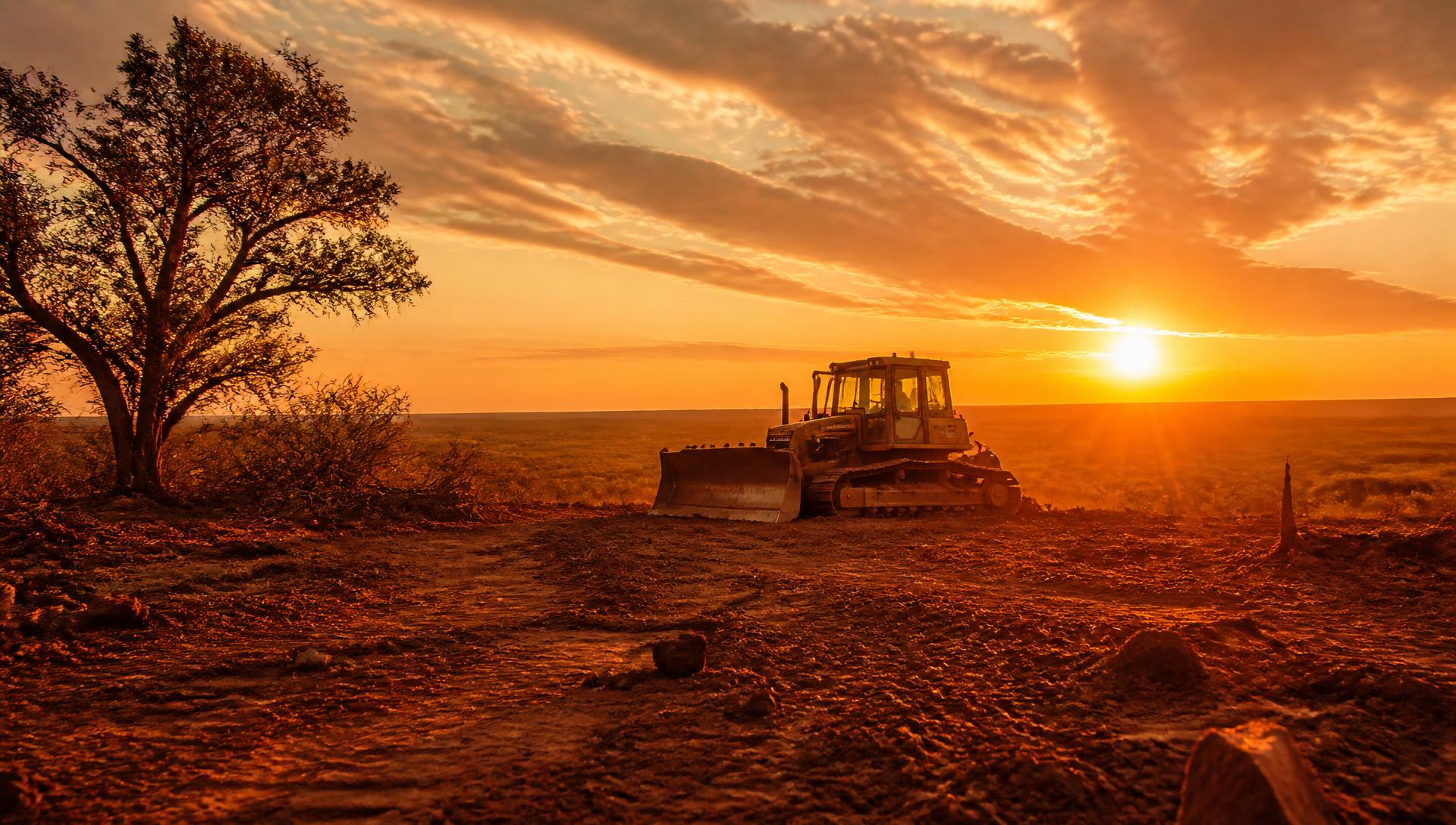 Dozer clearing Texas ranch land at golden hour